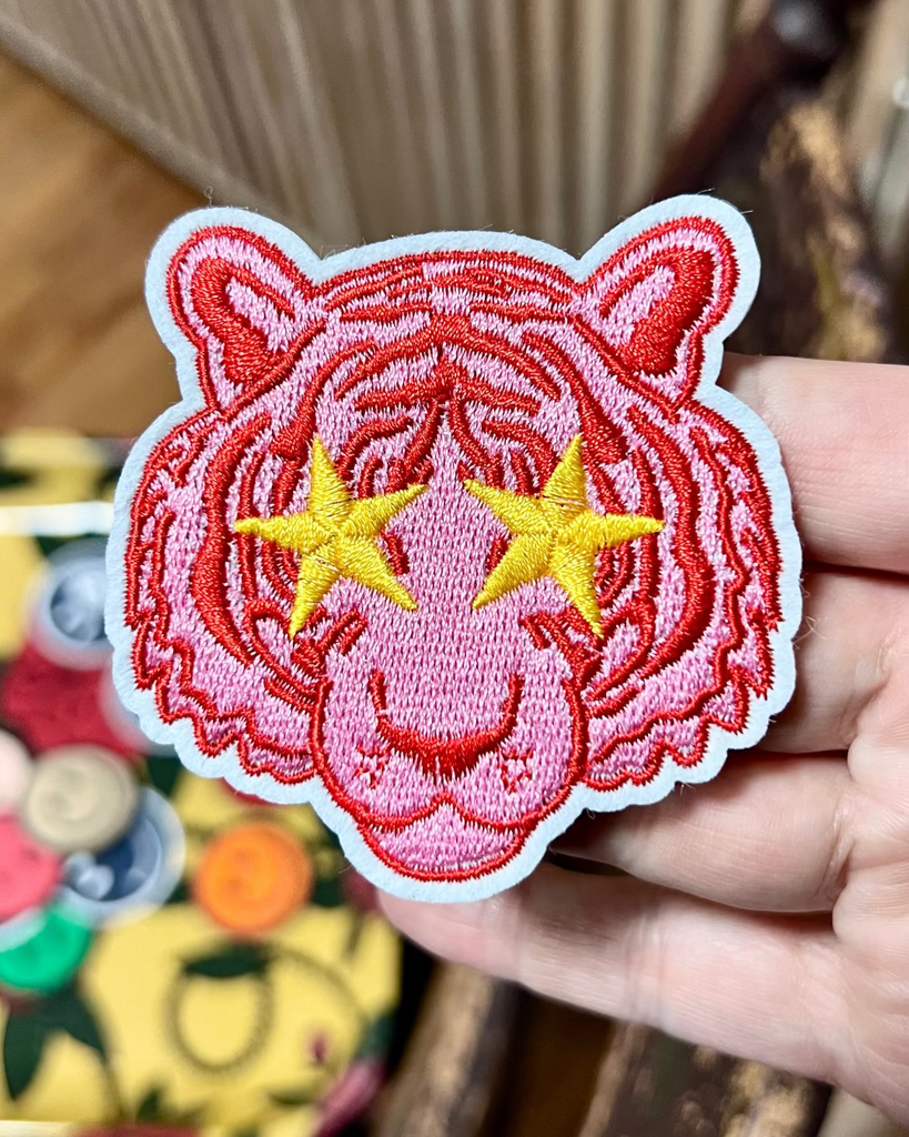Pink tiger with star eyes embroidered iron on patch sold by Le Monkey House